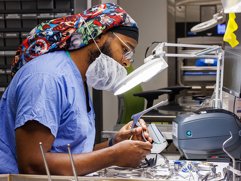 Children's of Mississippi Sterile Processing director Donteus Hubbard uses a magnifying glass to inspect surgical tools before they're sterilized for use.